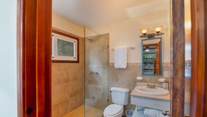 A bathroom with a glass-enclosed shower, a toilet, and a sink with a mirror above it. - Exclusive Full House near Beaches & Downtown (Roatan)