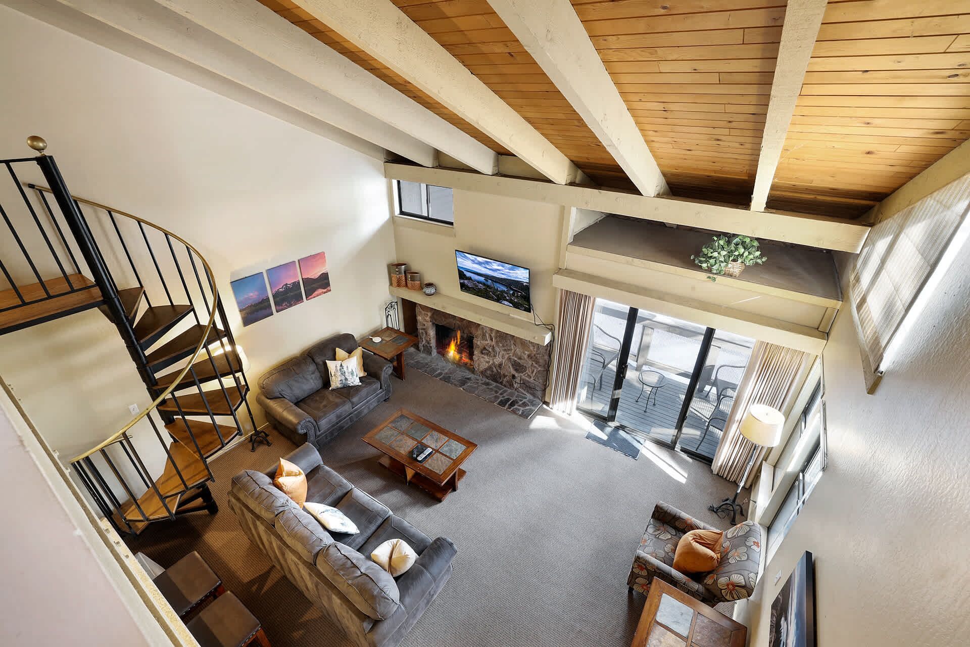 A spacious living room with a fireplace, a television, and a staircase leading to an upper level.