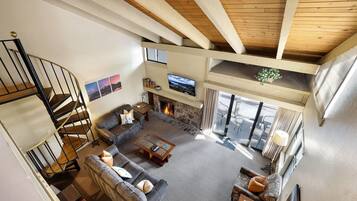 A spacious living room with a fireplace, a television, and a staircase leading to an upper level.