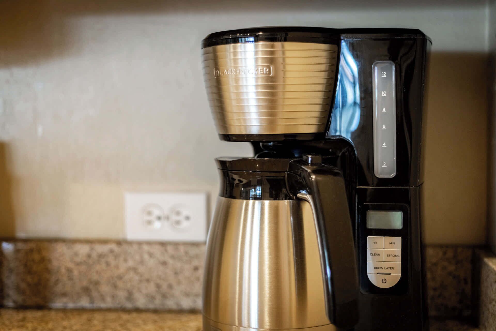 A black and gold coffee maker with a digital display and control buttons on a kitchen counter.