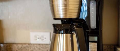 A black and gold coffee maker with a digital display and control buttons on a kitchen counter.