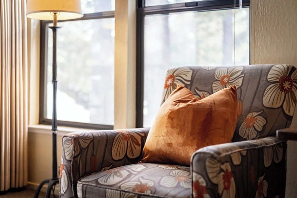 A chair with floral upholstery and a brown cushion, positioned near a window with a view of trees. - Lakeland Sandy Beach Retreat Private Escape (South Lake Tahoe)