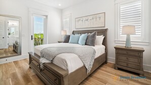 A bedroom with a large bed, a nightstand, a mirror, and a window with blinds.