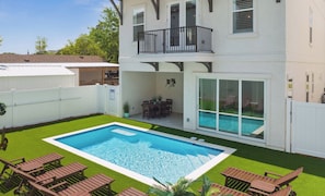 Et toetagers hus med swimmingpool, balkon og en patio med udendørs møbler.
