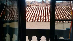 A view through a window with a tiled roof and a balcony with ornate balustrades. - Golden House Hotel  (Cusco)