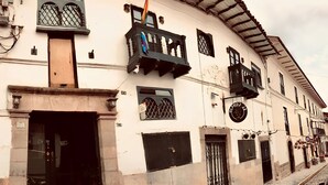 A historic building with a balcony, a large door, and a small window with a sign. - Golden House Hotel  (Cusco)