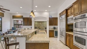 A modern kitchen with granite countertops, stainless steel appliances, and wooden cabinetry.