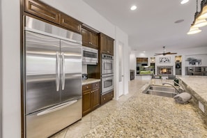 A modern kitchen with stainless steel appliances, a granite countertop, and a fireplace. - Casa De Amore: Pool, Spa, Casitas, Built-n BBQ! (Indio)