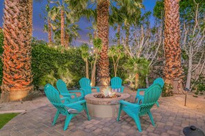A fire pit surrounded by chairs in an outdoor setting with palm trees. - Casa De Amore: Pool, Spa, Casitas, Built-n BBQ! (Indio)