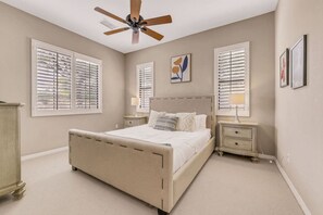 A bedroom with a bed, two bedside tables, a ceiling fan, and a window with blinds. - Casa De Amore: Pool, Spa, Casitas, Built-n BBQ! (Indio)