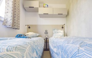 Twin beds with blue patterned sheets and a toy on the nightstand.