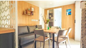 Un espacio habitable moderno con un muro de acento de madera, un sofá, una mesa de comedor con sillas y una planta decorativa.