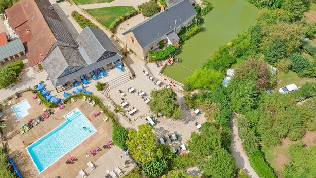 Vista aérea de un hotel con piscina, mobiliario exterior y un río.