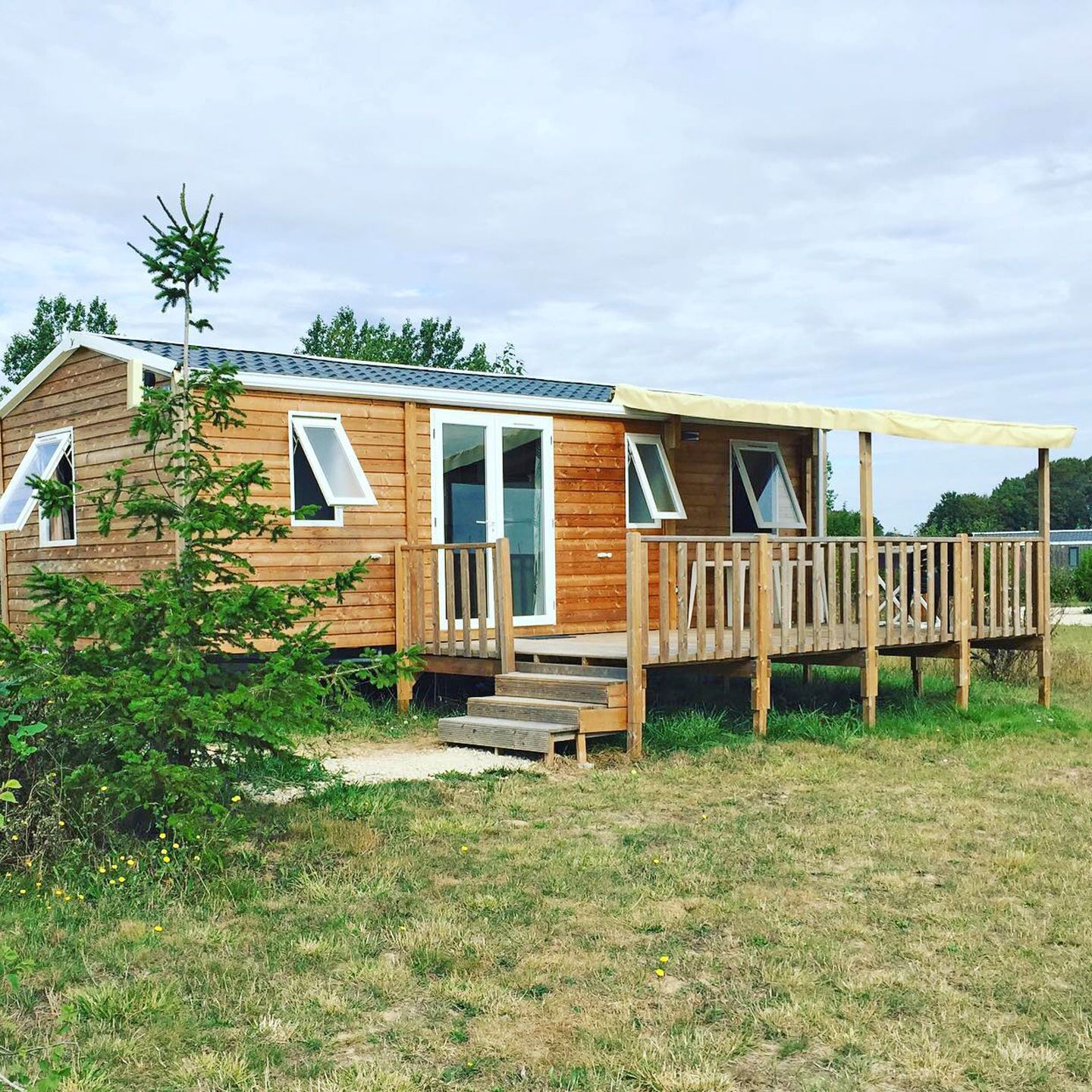 Une cabane en bois dotée d’une terrasse, d’un porche couvert et d’un petit escalier menant à l’entrée.