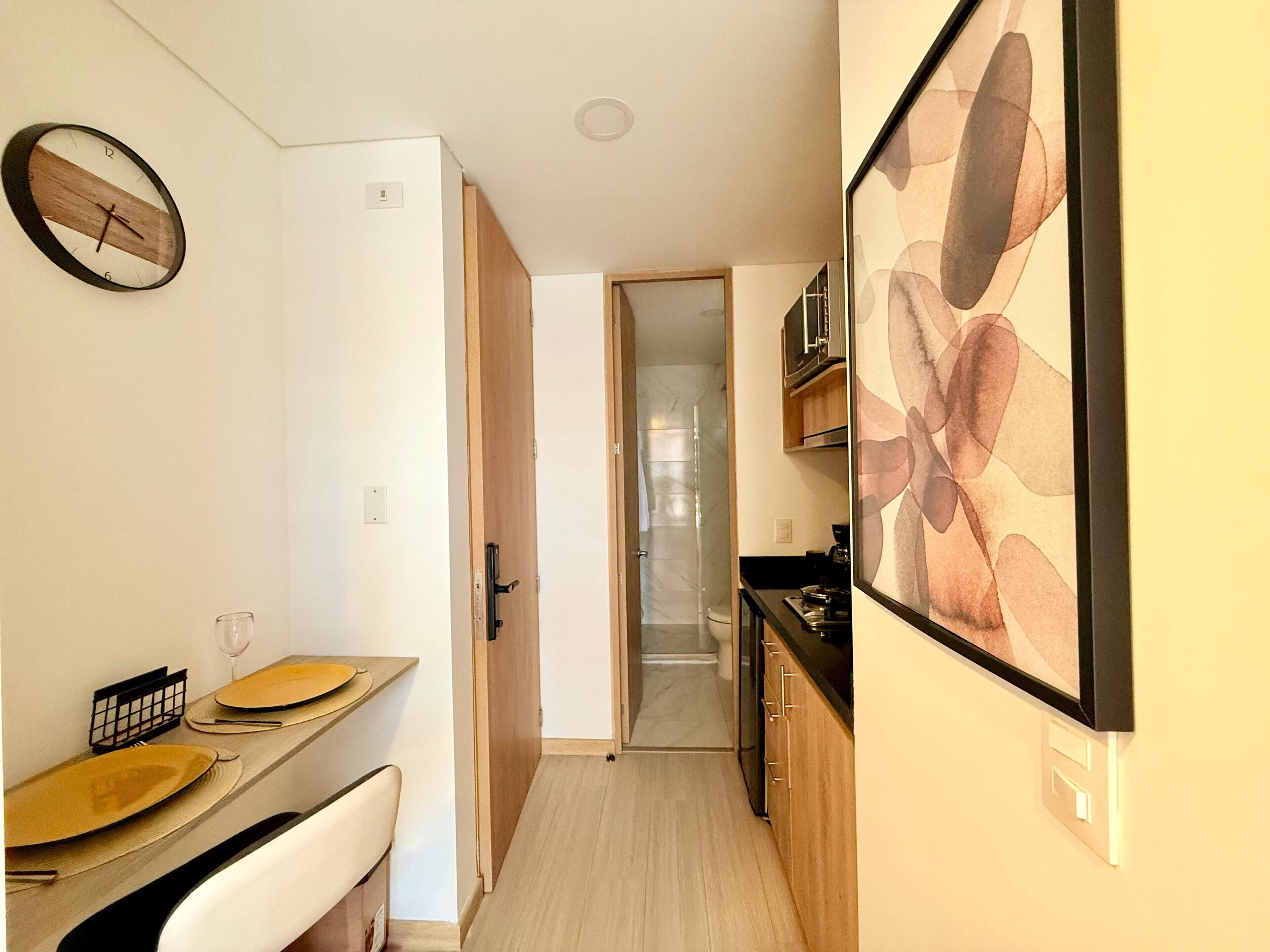 Un pasillo estrecho con comedor a un lado, zona de cocina al otro y baño al final.