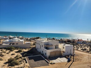 Ein Küstenwohngebiet mit weißen Gebäuden, einem Sandstrand und einem klaren, blauen Meer.