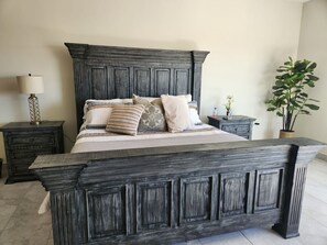Ein großes Bett mit dunklem Holz-Kopfteil, begleitet von zwei Nachttischen mit Lampen und einem Blumentopf.