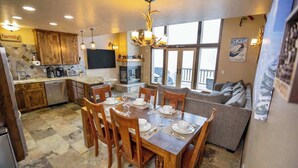 A spacious kitchen with wooden cabinets, a dining table set for six, and a large window overlooking a deck. - Kirkwood Mountainside Cabin w/Views, Walk to Lifts (Kirkwood)