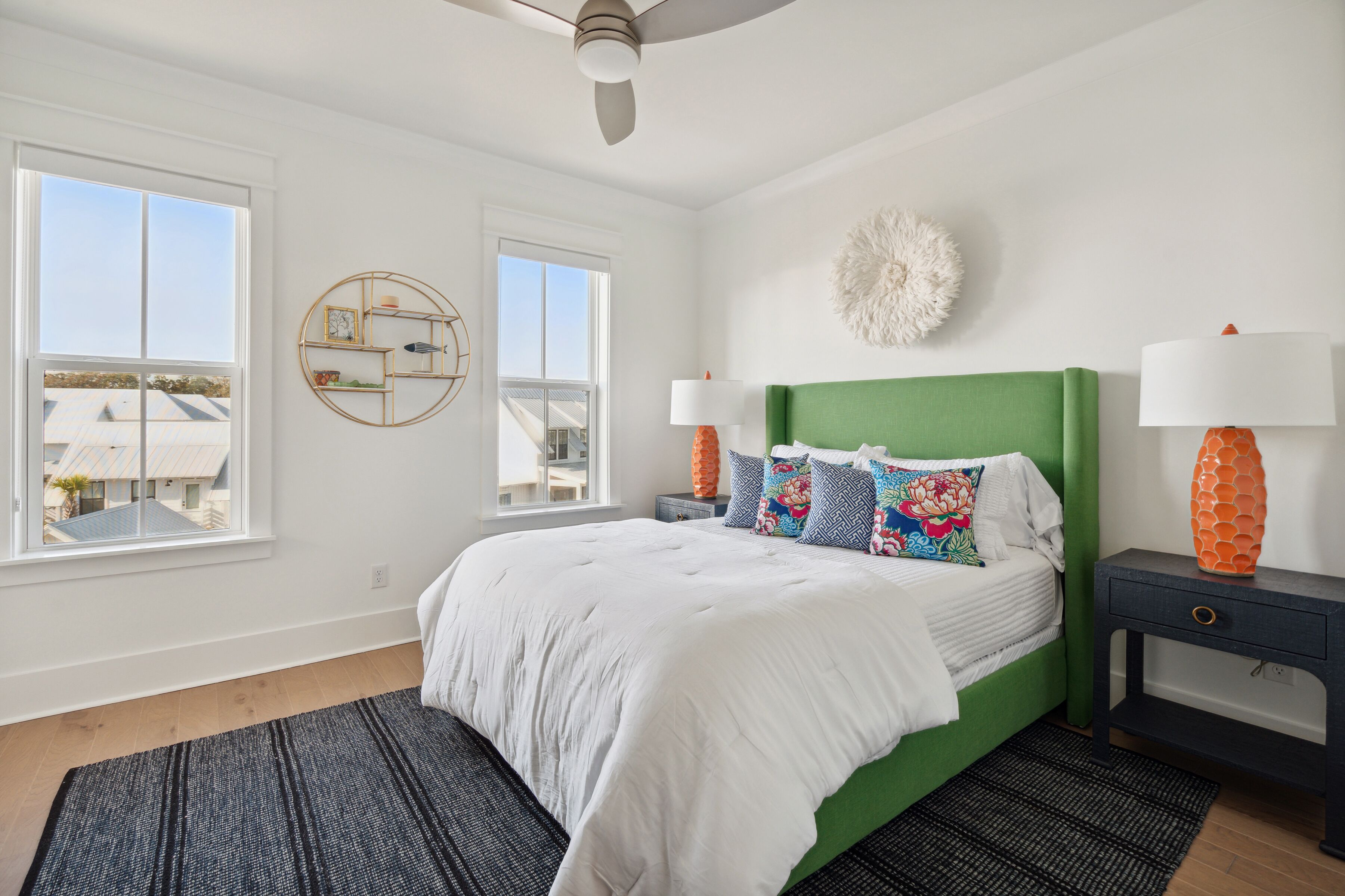 Un dormitorio con cabecera verde, ropa de cama blanca y dos lámparas de noche.