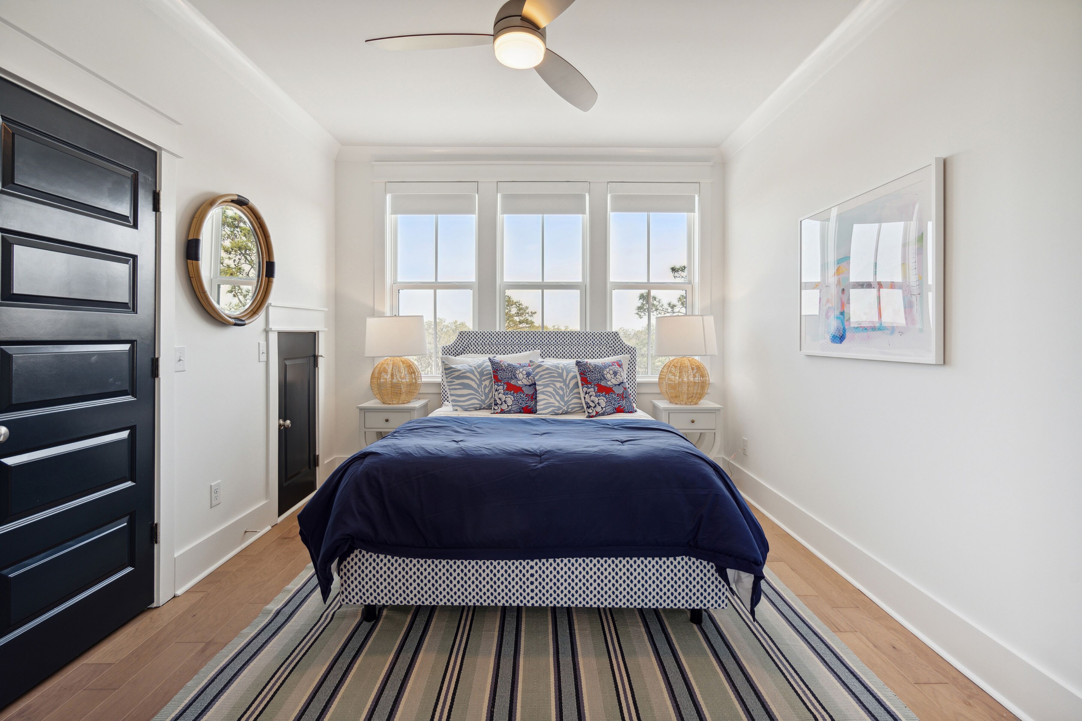 A bedroom with a bed, a ceiling fan, a window, and a door.