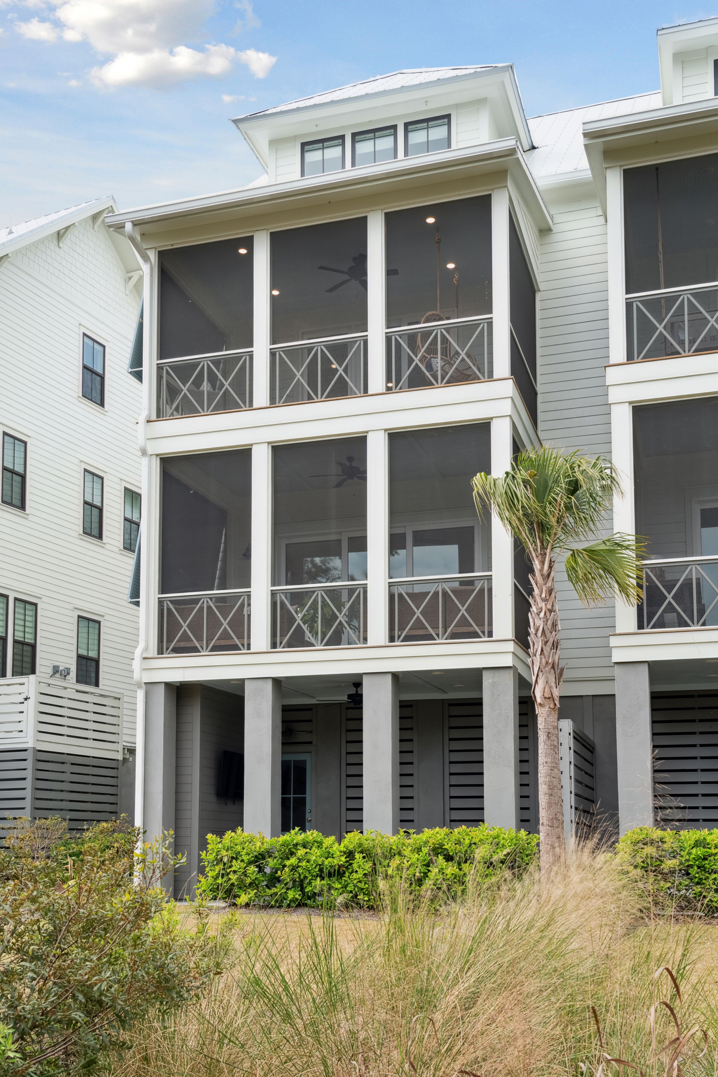 Un edificio de varios pisos con balcones, ventanas amplias y una palmera al frente.