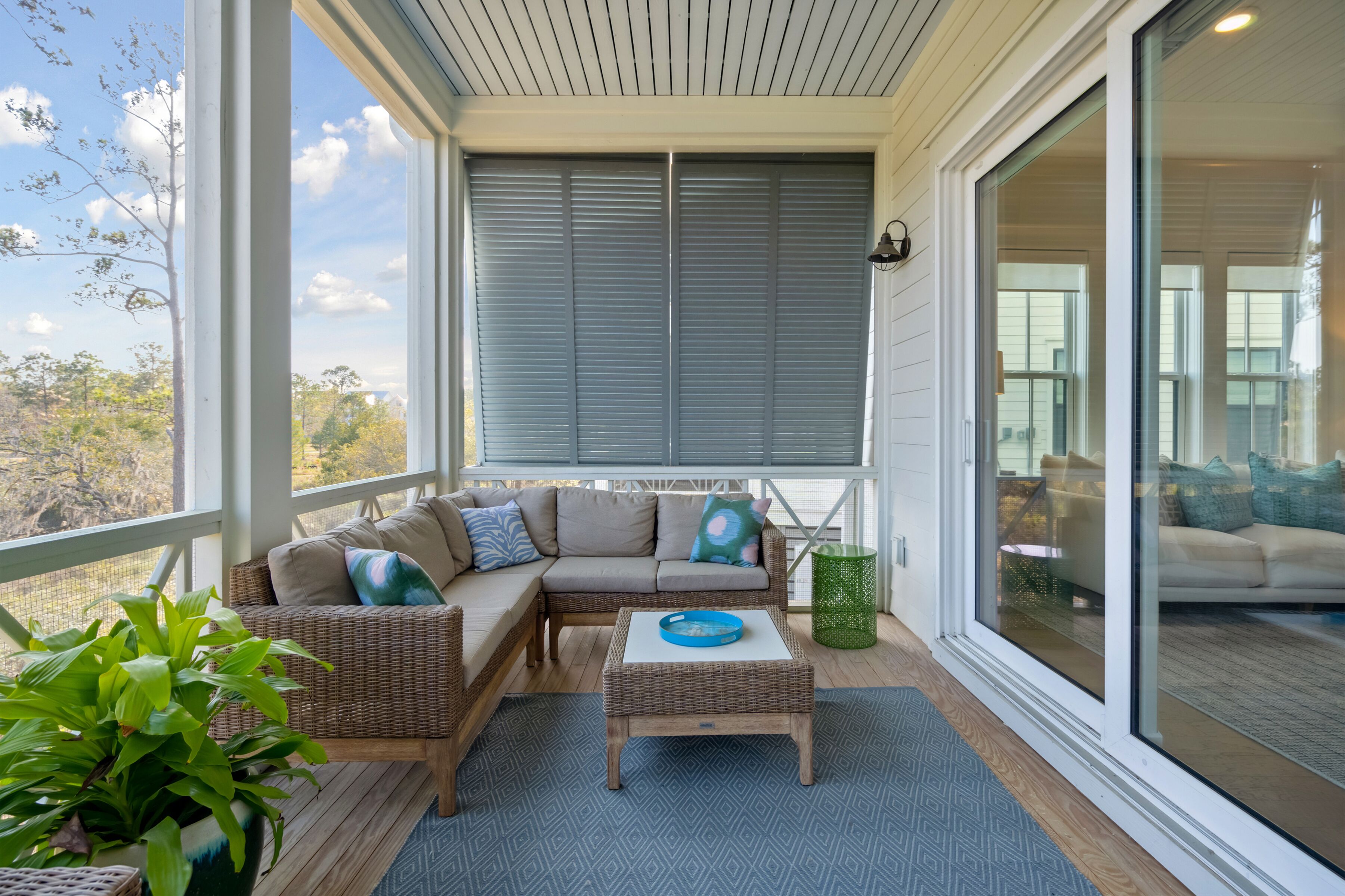 A covered porch with a wicker sofa, a small table, and a potted plant.