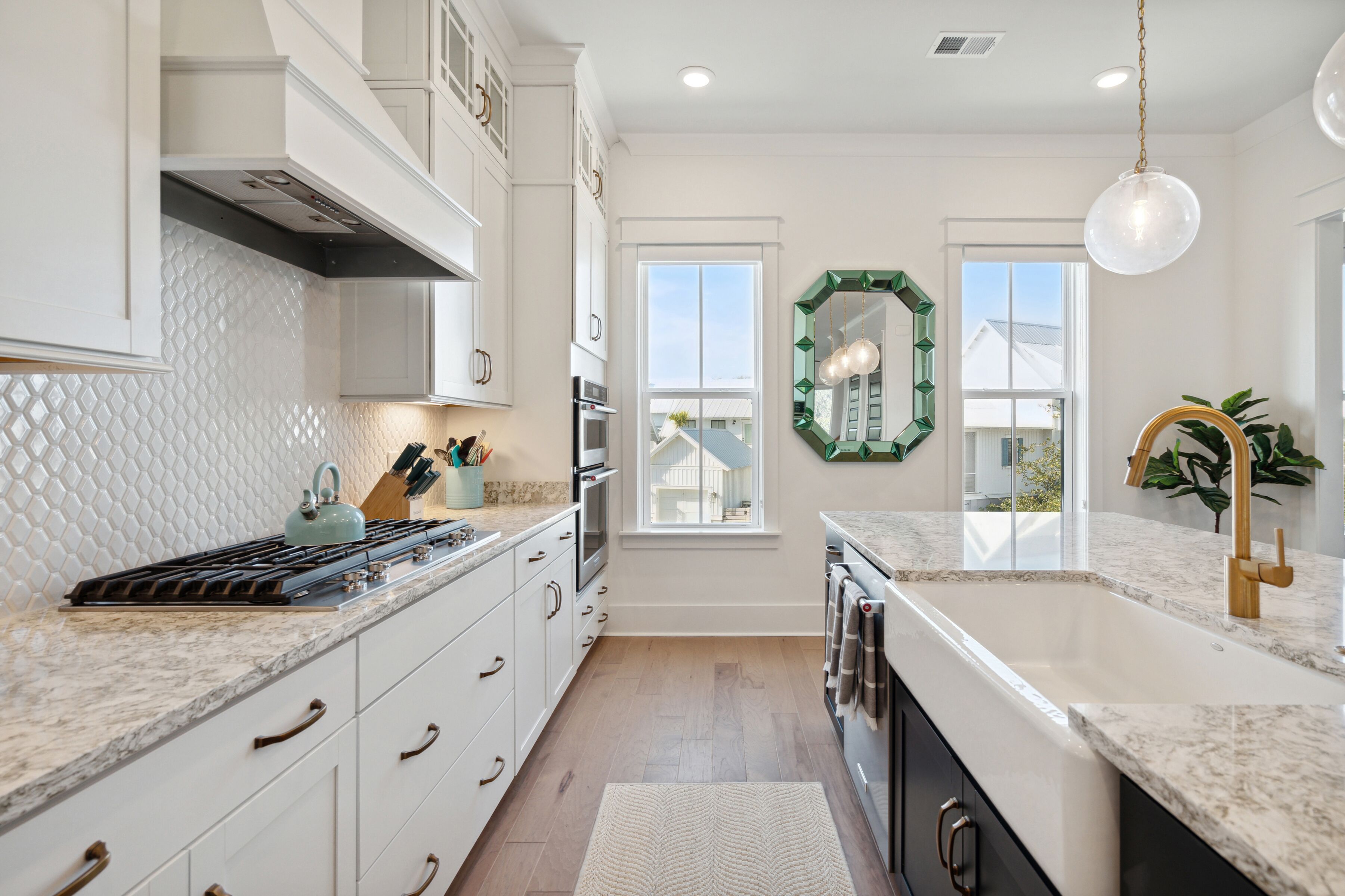 A modern kitchen with white cabinetry, a granite countertop, a gas stove, and a large window.