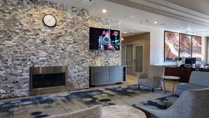 A modern lobby with a stone wall, a flat-screen TV, a fireplace, and comfortable seating.