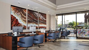 A reception area with a desk, chairs, artwork, and a view of the outside.