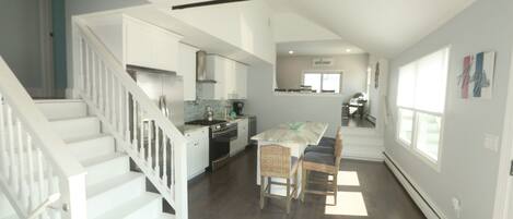 A spacious kitchen with a dining area, a staircase, and a view of the living area.
