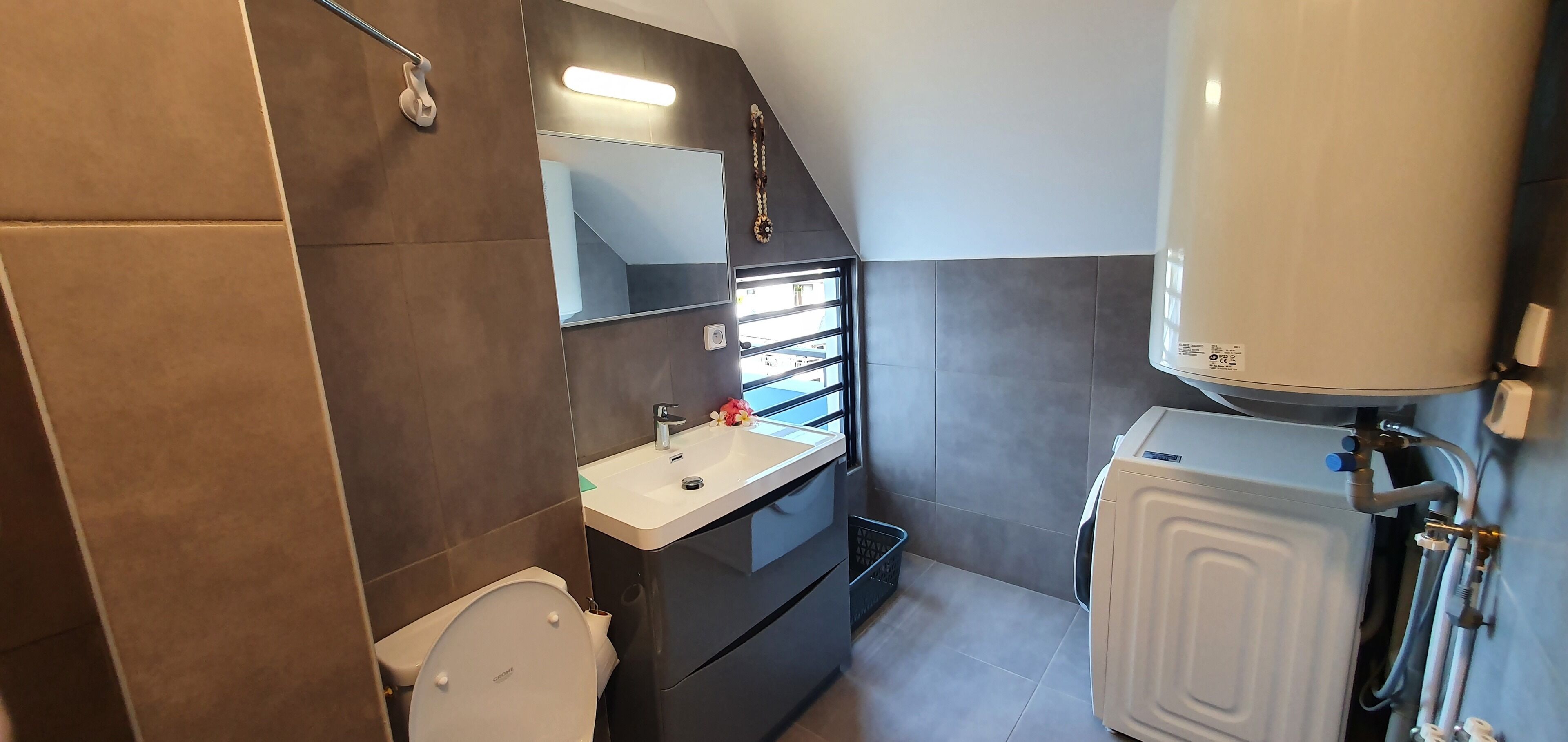 Ein kleines Badezimmer mit Toilette, Waschbecken, Spiegel und Warmwasserbereiter.