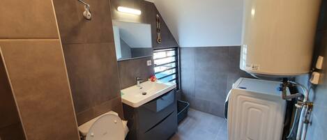 Ein kleines Badezimmer mit Toilette, Waschbecken, Spiegel und Warmwasserbereiter.