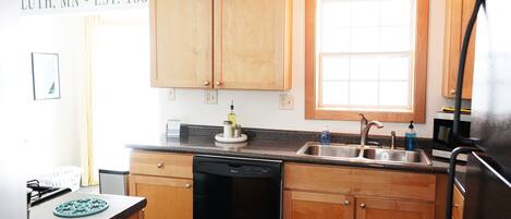 A kitchen with wooden cabinets, a dishwasher, a sink, and a window.