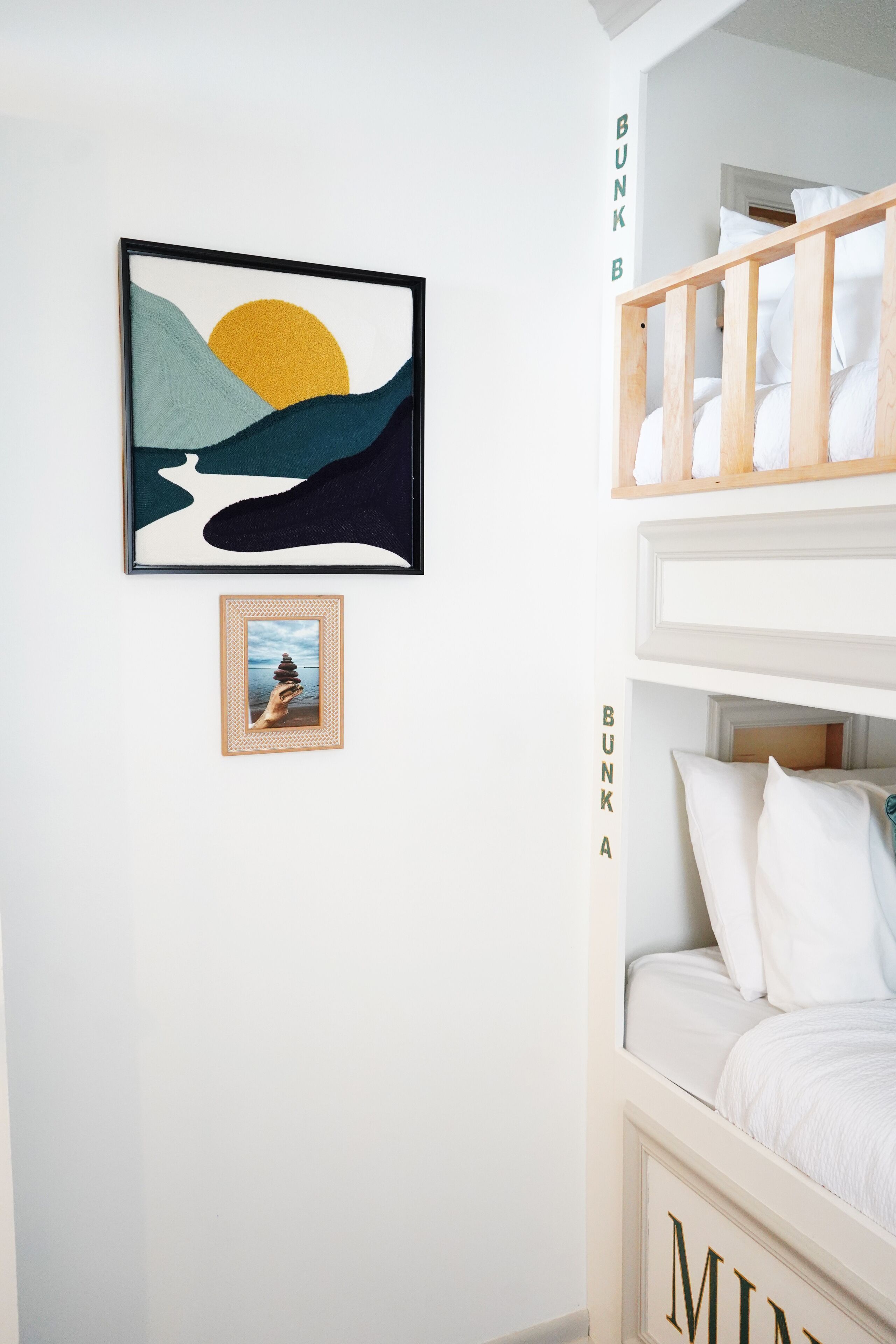 A bunk bed with a white headboard and a framed picture below it.