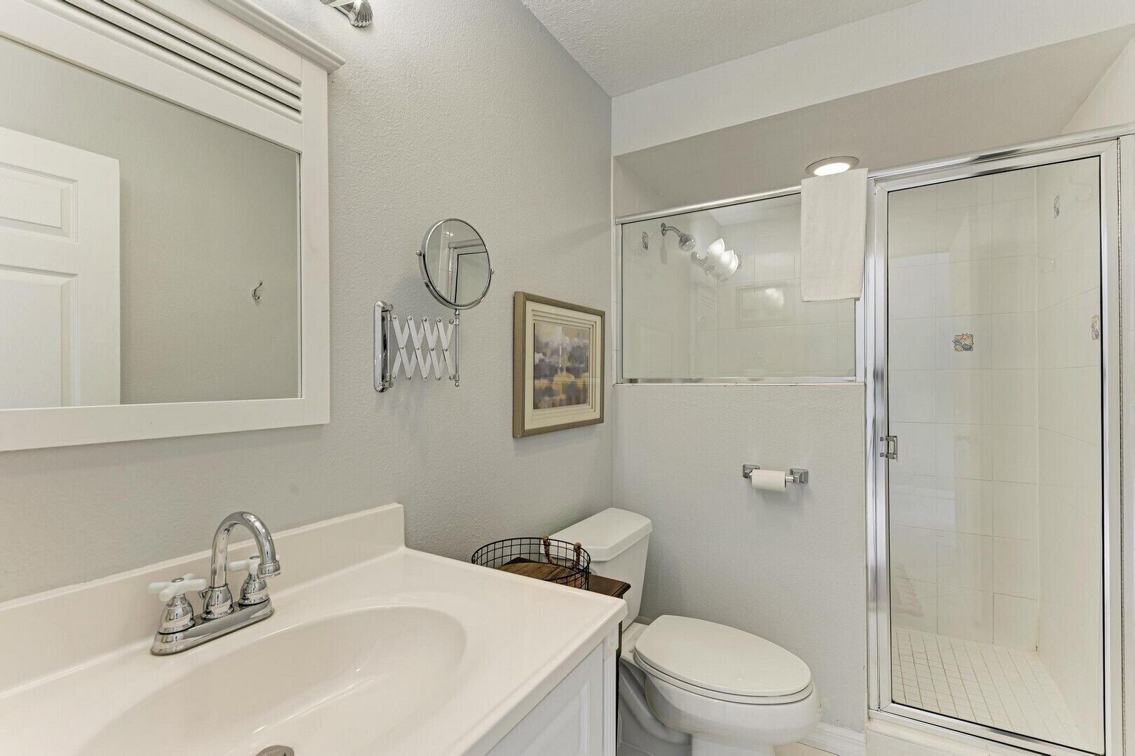 Une salle de bain avec un lavabo blanc, des toilettes et une douche à parois de verre.
