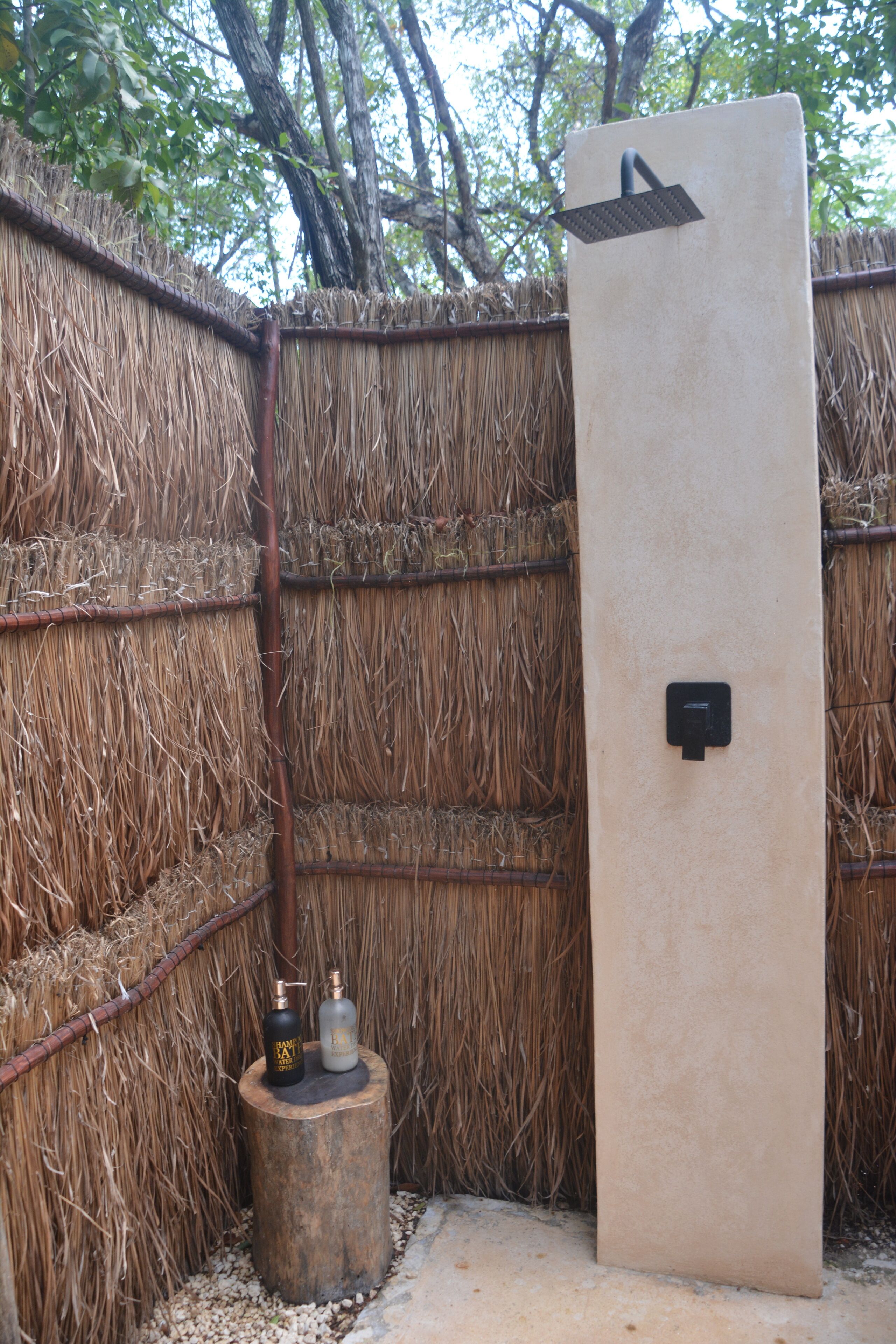 A thatched wall, a wooden stool, and a beige door with a black handle.