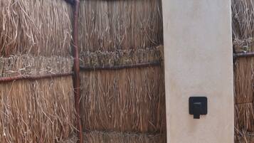A thatched wall, a wooden stool, and a beige door with a black handle.