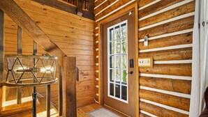 A wooden cabin interior with a staircase, a door with a window, and a wall-mounted thermostat. - Hocking Hills Secluded Cabin • Hot Tub • Fireplace (Logan)