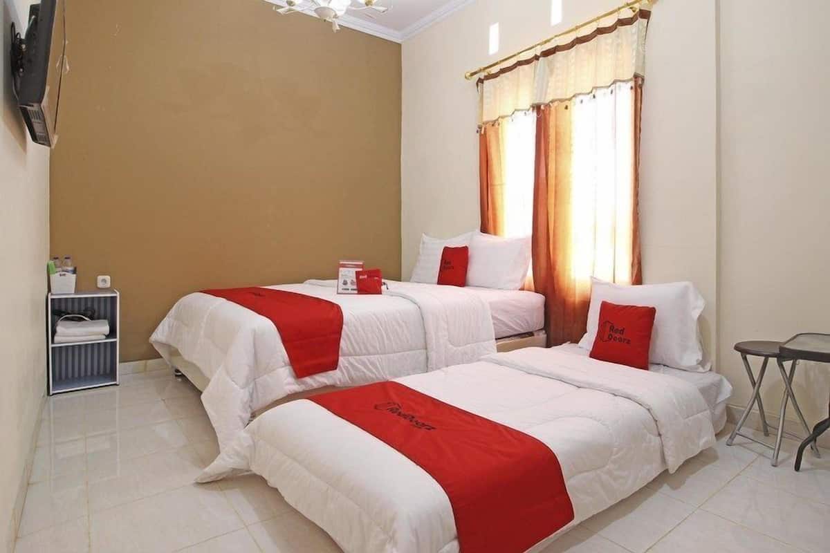 Habitació d'hotel amb dos llits, una taula petita i una estant amb productes de tocador.