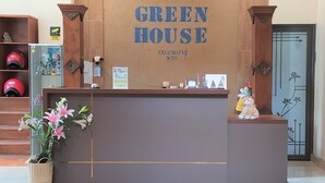 Taulell de recepció amb el rètol 'GREEN HOUSE', una planta en test i una petita estàtua.