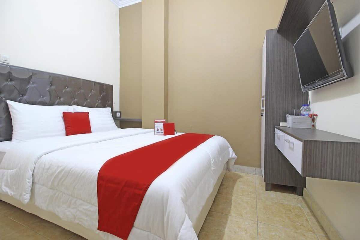 Habitació d'hotel amb un llit, una televisió i una petita taula de nit amb calaixos.