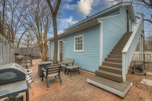 A blue house with a wooden deck, outdoor seating, and a barbecue grill. - Columbus Cottage, .5 Miles to Main, Private Hot Tub! (Fredericksburg)