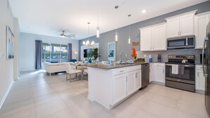A modern kitchen with white cabinets, stainless steel appliances, and a large island.