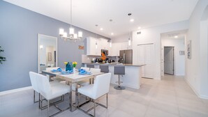 A modern kitchen with white cabinets, a central island, and pendant lighting.