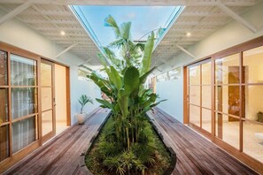 Stroll through a serene corridor lined with lush plants and natural light.