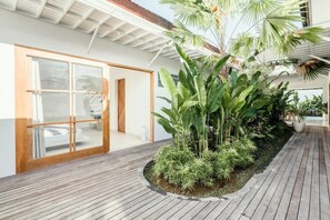 Step out onto the deck surrounded by lush tropical plants and enter through the glass door into a serene outdoor space.