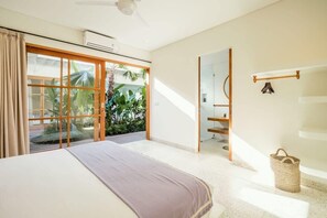 Relax in a spacious room with a large bed, sliding glass door to a balcony, and a ceiling fan for comfort.