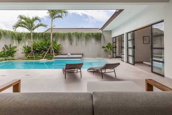 Relax by the pool surrounded by lush greenery and palm trees.