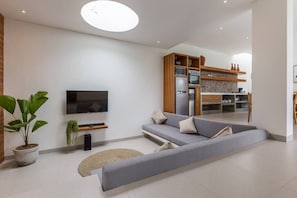 Relax in this stylish living room with a large sofa, flat-screen TV, and potted plant.
