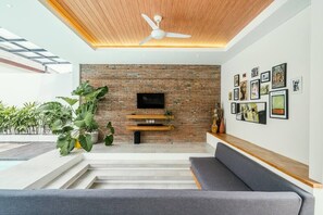 Relax in this stylish living room with a flat-screen TV, comfortable sofa, and a beautiful staircase leading to the upper level.
